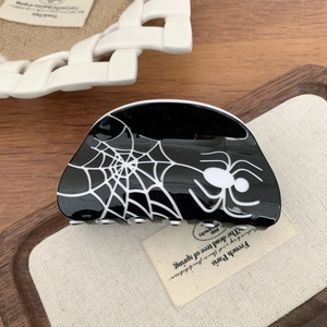 Macro detail of gothic black hair claw clip with white spider web and spider pattern