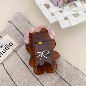 Close-up of a brown acetate hair claw clip with a cute bear head and pink headphone detail
