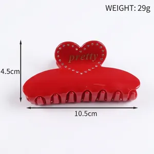 Macro detail of red large hair claw clip with rhinestones heart and gold pretty text