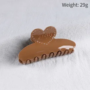 Detail view of large heart hair claw clip with rhinestones and pretty text engraving