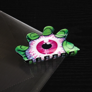 Détail d'une pince à cheveux œil effrayant avec doigts verts pour coiffure de Halloween