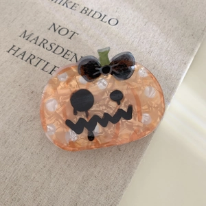 Detailed view of orange pumpkin hair claw clip with black bow for Halloween accessories