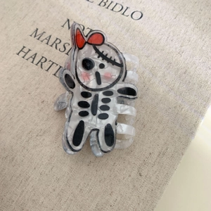 Macro detail of acrylic skull hair claw with pearlescent finish and red bow decoration