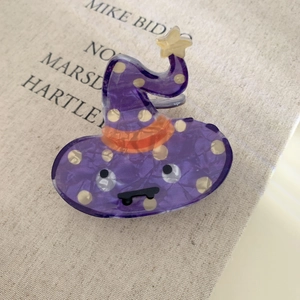 Close-up of a purple acrylic wizard hat hair claw clip with star and cute face details