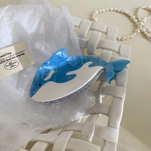 Détail de la pince à cheveux baleine en acétate marbré bleu sur panier tressé blanc