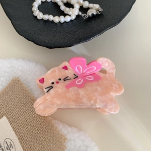 Close-up of pink marble acetate cat hair claw clip with floral bow detail on a stylist setup