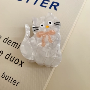 Detail view of a white marble acetate cat hair claw clip with a pink bow decoration