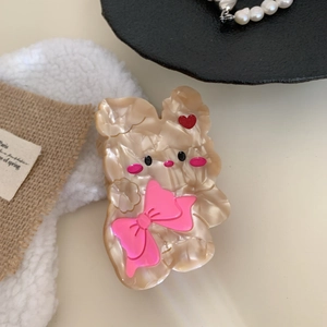 Dettaglio di un fermaglio per capelli beige marmorizzato con fiocco rosa e cuori
