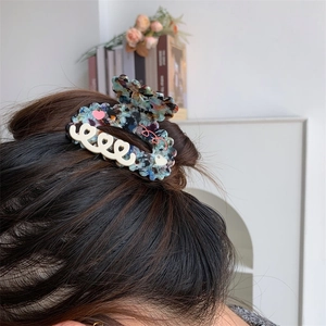 Pince à cheveux ondulée en acétate coloré avec motifs de cœurs portée sur les cheveux
