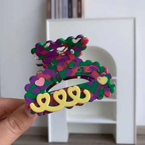 Détail d'une pince à cheveux en acétate coloré avec motifs de cœurs et bords ondulés