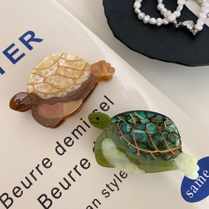 Pinces à cheveux tortue élégantes en acétate avec bords dorés sur fond en toile blanche