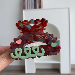Détail d'une pince à cheveux en acétate avec bords ondulés et découpes en cœur