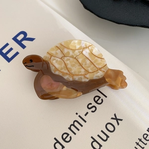 Vue détaillée de la pince à cheveux tortue en acétate avec des motifs de lignes dorées