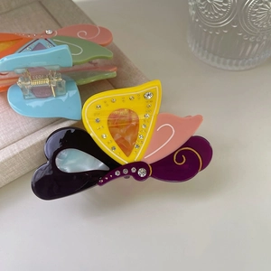 Dettaglio di una pinza per capelli a farfalla in acetato colorato con strass incastonati
