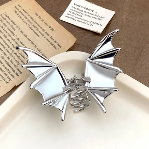 Makro-Detail der silbernen Fledermaus-Haarklammer aus Metall auf Vintage-Buchseiten