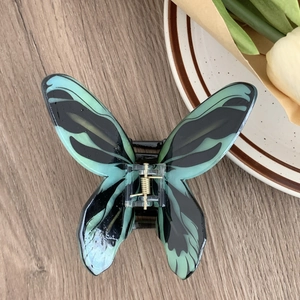 Gros plan détaillé d'une pince à cheveux papillon réaliste avec motif marbré vert et noir
