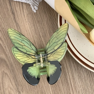 Vue détaillée de dessus d'une pince à cheveux papillon vert dégradé sur table en bois