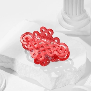 Elegant translucent red hair claw clip with Chinese knot hollow pattern on white stone surface