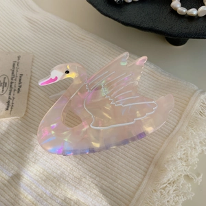 Detail of pink swan hair claw clip with pearlescent finish on white knit fabric