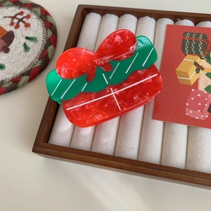 Detail of red and green Christmas gift box hair claw clip on a wooden jewelry tray