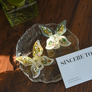 Macro shot of butterfly acetate hair claws with colorful rhinestones on a glass tray