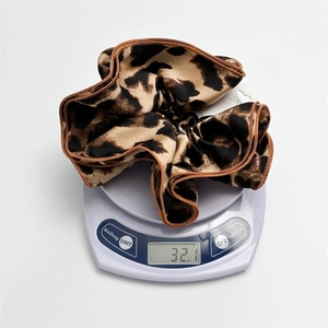 Double-layered leopard print scrunchie in velvet fabric weighing 32.1g on a white scale