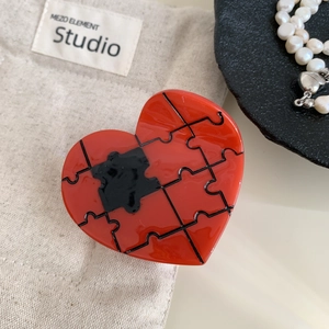 Detailed close-up of a glossy red heart-shaped puzzle hair claw with mirror finish
