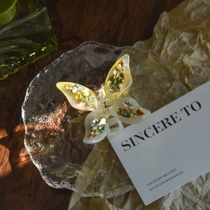 Detailed close-up of a butterfly hair claw clip with colorful rhinestones on glass tray