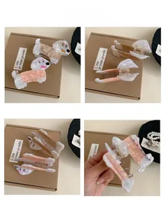 Detailed view of dachshund-shaped hair clips in cream and pink marble acetate finish