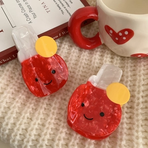 Set of two red and white smiley face hair clips on a soft knit background with a cozy ceramic cup