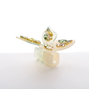 Detail view of acetate butterfly hair claw with colorful rhinestones on a cream base