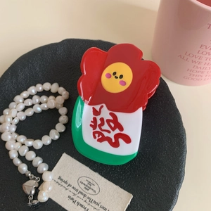 Détail d'une pince à cheveux fleur aux pétales rouges et cœur jaune souriant