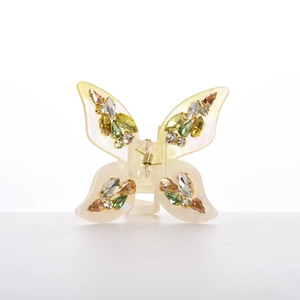 Macro detail of butterfly hair claw clip with colorful rhinestones and pearly white acetate