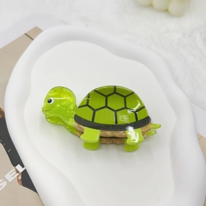 Detail showing the glossy green acrylic sea turtle hair claw clip with black shell patterns