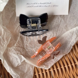 Detail view of black and amber acrylic cat-shaped hair claws with silver springs