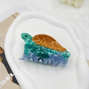 Detail of sea turtle hair claw clip with green marble texture on a ceramic plate