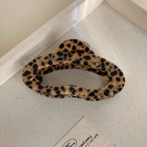 Detailed macro view of large leopard print cellulose acetate hair claw with gold spring