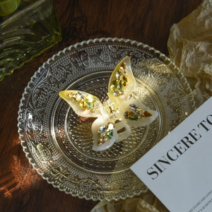 Elegant butterfly hair claw clip with crystals on pearlescent resin in a glass tray