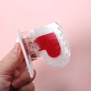 Detailed shot of a creamy white heart hair claw clip with red heart and colorful rhinestones