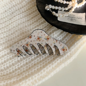 Detail of floral pattern hair claw clip on soft knitted fabric with elegant accessories