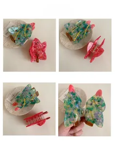 Close-up of acetic acid Christmas tree hair claw with glitter details and metal spring