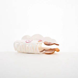 Detail view of a white acetate hair claw clip with a cute brown animal print and spiral patterns
