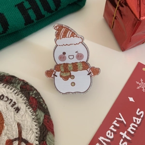 Nahaufnahme einer festlichen Acryl-Schneemann-Haarklammer mit orangefarbenem Glitzer