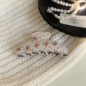 Detail of floral acrylic hair claw clip with vintage pattern and black inner teeth