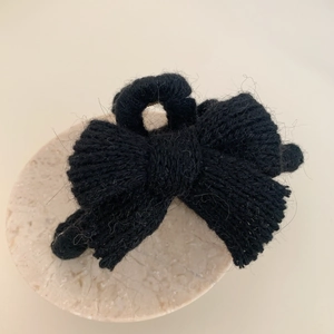 Vue détaillée d'une pince à cheveux à nœud tricoté noir avec texture en laine