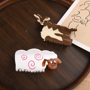 Cute animal acetate hair claws featuring sheep and goat designs on a wooden tray