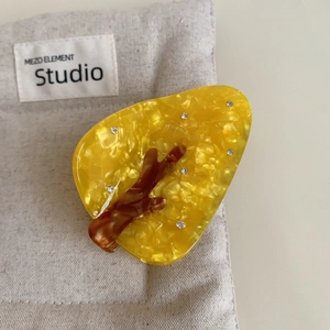 Detailed close-up of a yellow acetate Christmas tree hair claw clip with rhinestones