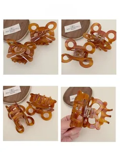 Detail view of amber tortoise hair claw with white polka dots and hollow bow design