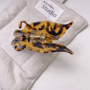 Close-up of tortoise shell pattern acetate hair claw clip with golden metal spring
