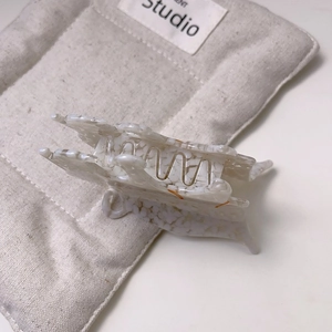 Detail view of a cream marble pattern acetate leopard claw clip with metal spring